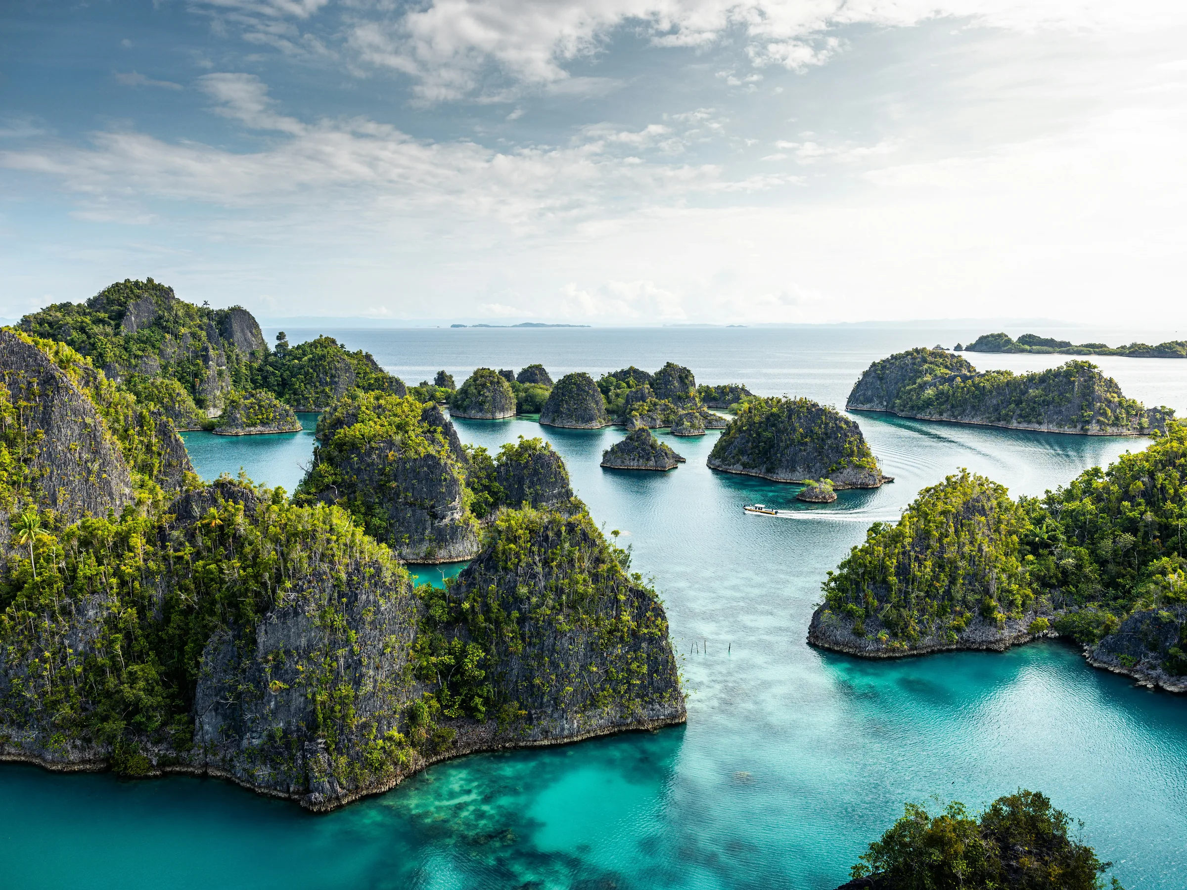 Aerial view of turquoise lagoons between jungle-covered limestone islands